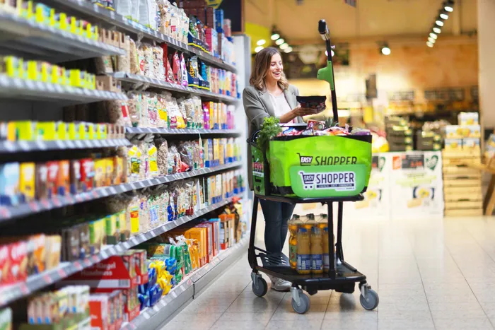 Happy shopper with a smart shopping cart browsing items in the grocery store aisle